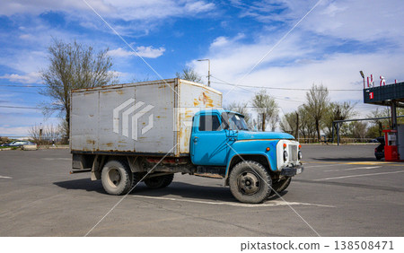 Old blue cargo truck sits idle near fuel pump under bright sky Old blue cargo truck sits idle near fuel pump under bright sky 138508471