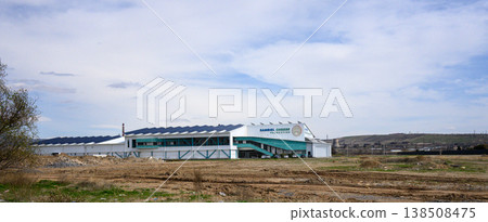 Greenhouse facility stretches across open field under overcast sky Greenhouse facility stretches across open field under overcast sky 138508475