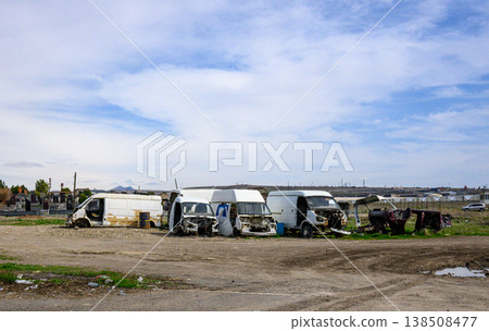 Abandoned white vans lined up in dirt field under cloudy sky 138508477