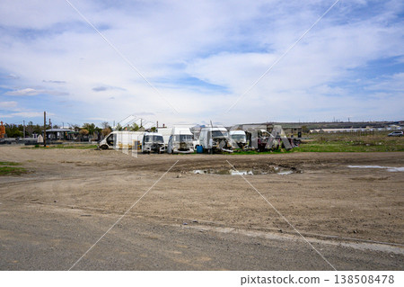 Row of trucks parked on dry, dusty ground under a cloudy sky 138508478