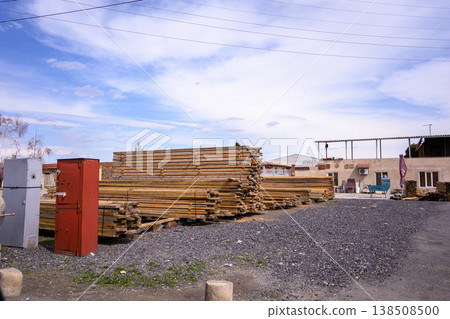 Lumber piles, storage containers, and open yard under bright sky 138508500
