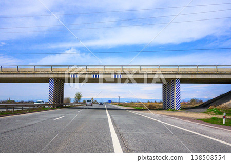 Long straight road under modern bridge with striped pillars Long straight road under modern bridge with striped pillars 138508554