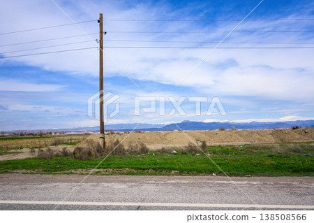 Pole with wires near road under sunny sky 138508566