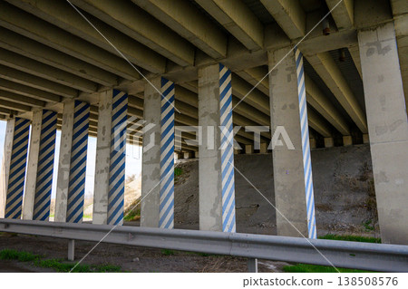 Underneath highway overpass, striped concrete support columns 138508576