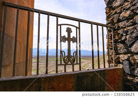 Metal railing with ornate cross gate overlooks mountainous landscape Metal railing with ornate cross gate overlooks mountainous landscape 138508625