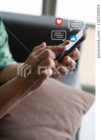 Close-up of a person using smartphone with social media icons, like, heart, and chat notification, representing online communication, social interaction, and digital connection in modern lifestyle. 138508664