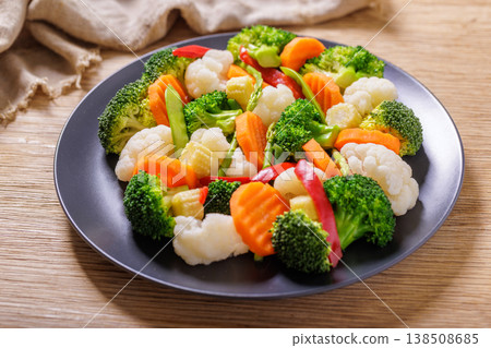 plate of mix of steamed vegetables on wooden table 138508685