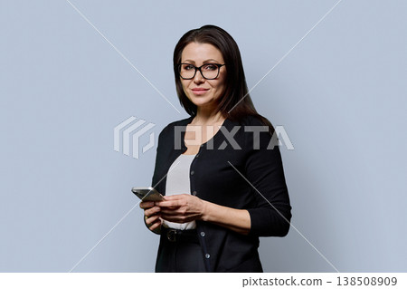 Portrait mature woman with smartphone on grey studio background 138508909