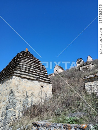 Dargavs City of the Dead necropolis, North Ossetia, Russia. Historic burial site with rows of white crypts stretching across the green landscape Dargavs City of the Dead necropolis, North Ossetia, Russia. Historic burial site with rows of white crypts stretching across the green landscape 138508926