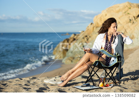 Businesswoman with glass of whiskey on seashore Businesswoman with glass of whiskey on seashore 138509082