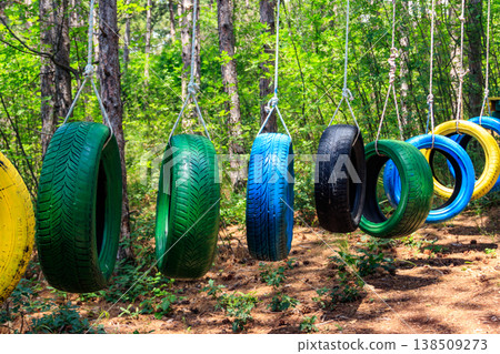 Old painted car tires suspended between trees in a rope park Old painted car tires suspended between trees in a rope park 138509273