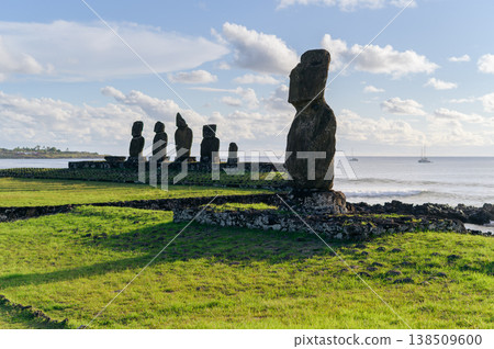 Majestic moai statue stands with stoic emotion on green coast of easter island known as rapa nui overlooking deep blue ocean under bright daytime sky with soft white cloud Majestic moai statue stands with stoic emotion on green coast of easter island known as rapa nui overlooking deep blue ocean under bright daytime sky with soft white cloud 138509600