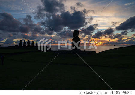 Majestic moai sculpture stands as mysterious silhouette against dramatic sunset sky overlooking vast ocean on easter island rapa nui evoking profound awe and peaceful wonder Majestic moai sculpture stands as mysterious silhouette against dramatic sunset sky overlooking vast ocean on easter island rapa nui evoking profound awe and peaceful wonder 138509623