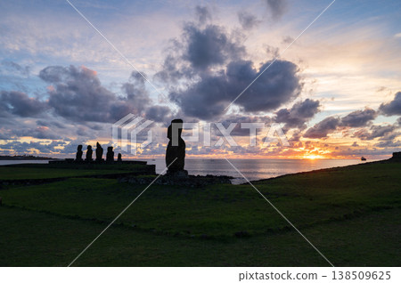Serene moai statue of rapa nui faces beautiful warm sunrise over easter island ocean creating dark silhouette monument representing deep ancient travel history 138509625
