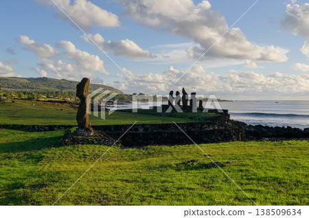 Ancient majestic moai statue stands on lush green grass field overlooking peaceful blue ocean coast of beautiful easter island rapa nui under cloudy sky Ancient majestic moai statue stands on lush green grass field overlooking peaceful blue ocean coast of beautiful easter island rapa nui under cloudy sky 138509634