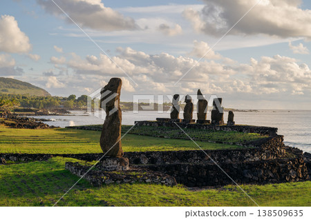 Majestic moai statue stands with calm stoic expression on green coast of ancient easter island rapa nui overlooking serene ocean under cloudy sky evoking deep sense of mystery Majestic moai statue stands with calm stoic expression on green coast of ancient easter island rapa nui overlooking serene ocean under cloudy sky evoking deep sense of mystery 138509635