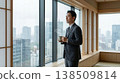 Business man holding tea and looking through window in modern office 138509814