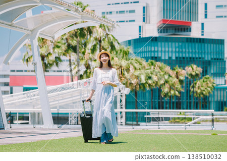 A young woman in a straw hat heading out for a resort vacation. A young woman in a straw hat heading out for a resort vacation. 138510032