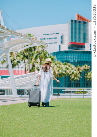 A young woman in a straw hat heading out for a resort vacation. 138510038
