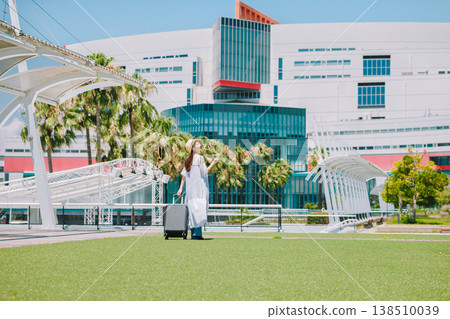 A young woman in a straw hat heading out for a resort vacation. 138510039