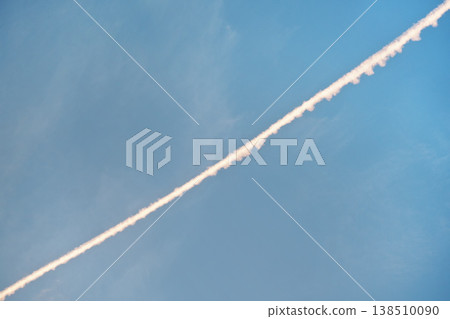 Airplane white pink condensation trail (also known as chemtrails in conspiracy theory)  painted diagonally over clear morning sky 138510090