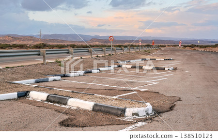 Parking lot spaces at rest area near main highway, desert landscape background 138510123