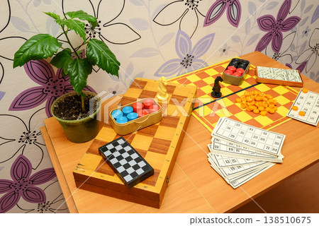 board games on a table by a wall with floral wallpaper and a houseplant 138510675
