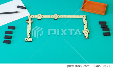 close up of domino knuckles on a green background next to a sheet of paper and a pen 138510677