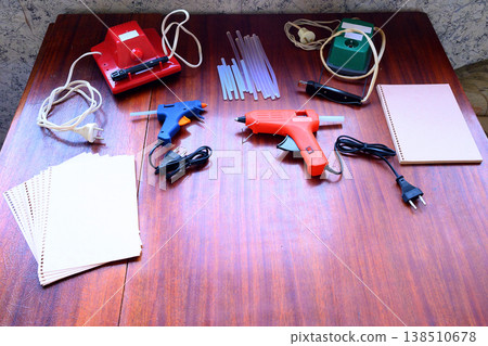 craft tools including glue guns and paper on a wooden table craft tools including glue guns and paper on a wooden table 138510678