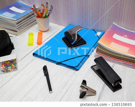 a blue folder and stationery items on the table at an angle to the camera 138510693