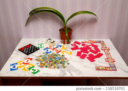 various board games, cards, puzzles and dominoes laid out on a light table near a plant various board games, cards, puzzles and dominoes laid out on a light table near a plant 138510701