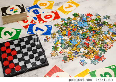 game set with puzzles, checkers and cards laid out on a light table surface game set with puzzles, checkers and cards laid out on a light table surface 138510705