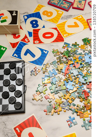 vertical view of a scatter of puzzle pieces and game cards on light marble vertical view of a scatter of puzzle pieces and game cards on light marble 138510709
