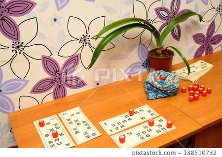 lotto cards and red barrels on a table next to a pouch and a plant lotto cards and red barrels on a table next to a pouch and a plant 138510732