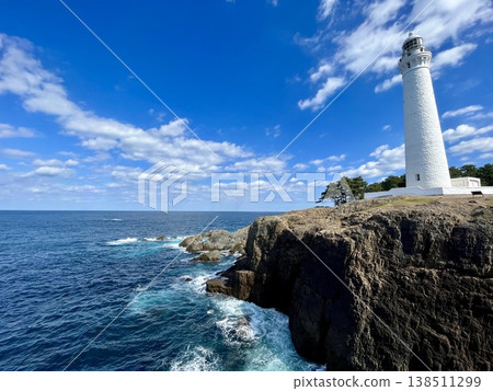 A white lighthouse standing on a cliff overlooking the Sea of Japan, against a blue sky. A white lighthouse standing on a cliff overlooking the Sea of Japan, against a blue sky. 138511299