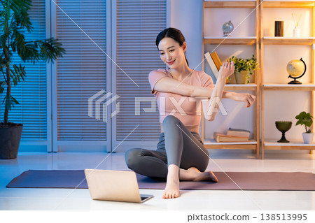 A woman stretching while looking at a computer 138513995