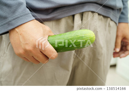 Male stands holding a cucumber, penis health. Male stands holding a cucumber, penis health. 138514166