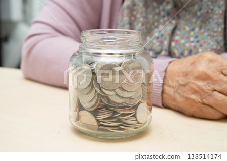 Retired Asian elderly woman counting coins money and worry about monthly expenses and treatment fee payment. Retired Asian elderly woman counting coins money and worry about monthly expenses and treatment fee payment. 138514174