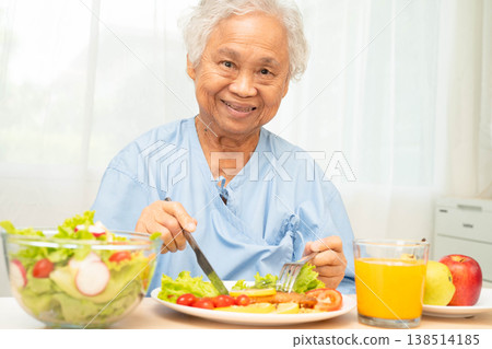 Asian elderly woman patient eating salmon stake and vegetable salad for healthy food in hospital. Asian elderly woman patient eating salmon stake and vegetable salad for healthy food in hospital. 138514185