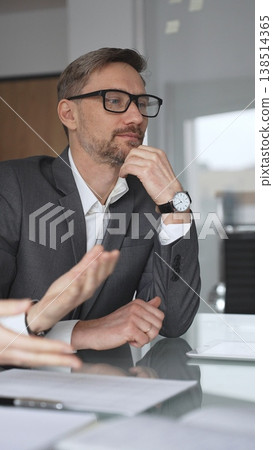 Business colleagues collaborating on an agreement, woman signing a document during a professional meeting in an office, man assisting her with information on a digital tablet, vertical view Business colleagues collaborating on an agreement, woman signing a document during a professional meeting in an office, man assisting her with information on a digital tablet, vertical view 138514365