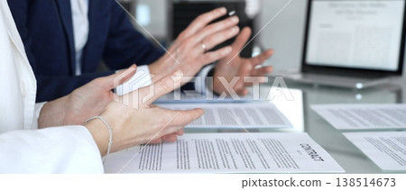 Business people are discussing a contract, reviewing documents and pointing with a pen, sitting at an office table with a laptop, focusing on agreement details and legal paperwork Business people are discussing a contract, reviewing documents and pointing with a pen, sitting at an office table with a laptop, focusing on agreement details and legal paperwork 138514673