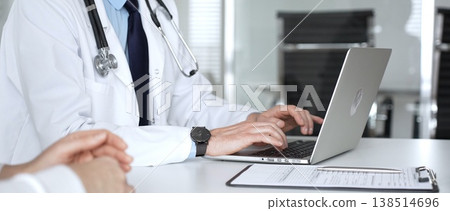 Doctor consulting patient, typing on laptop during medical check up in clinic, accessing electronic health records. Medicine, healthcare and science concept Doctor consulting patient, typing on laptop during medical check up in clinic, accessing electronic health records. Medicine, healthcare and science concept 138514696