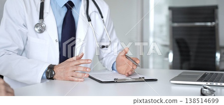 Doctor man in white coat and stethoscope consulting with a patient, writing notes on a clipboard during an appointment. Medicine, healthcare and science concept Doctor man in white coat and stethoscope consulting with a patient, writing notes on a clipboard during an appointment. Medicine, healthcare and science concept 138514699