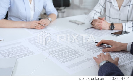 Business partners discussing contract terms, reviewing legal documents during an office meeting, focusing on agreement details and professional negotiation strategies Business partners discussing contract terms, reviewing legal documents during an office meeting, focusing on agreement details and professional negotiation strategies 138514705