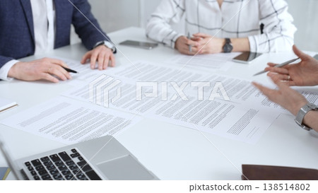 Professionals reviewing and signing contract documents across a white table, hands exchanging papers and pens to finalize negotiation, partnership and corporate agreement decisions Professionals reviewing and signing contract documents across a white table, hands exchanging papers and pens to finalize negotiation, partnership and corporate agreement decisions 138514802