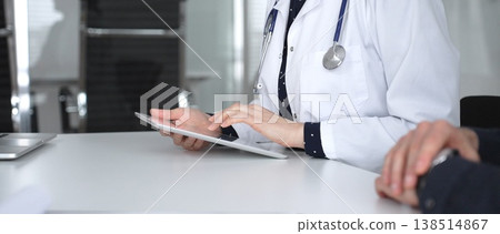 Doctor woman working on digital tablet during medical consultation with patient in clinic, discussing health information. Medicine, healthcare and science concept Doctor woman working on digital tablet during medical consultation with patient in clinic, discussing health information. Medicine, healthcare and science concept 138514867