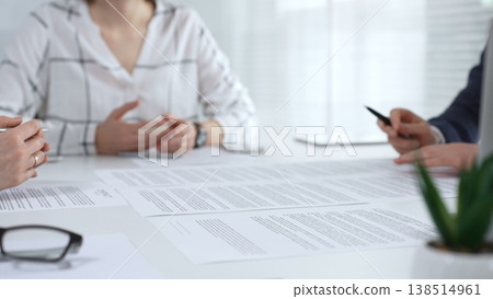 Business people collaborating at a conference table, reviewing paperwork, sharing ideas, and reaching a mutual agreement during a professional meeting or consultation Business people collaborating at a conference table, reviewing paperwork, sharing ideas, and reaching a mutual agreement during a professional meeting or consultation 138514961