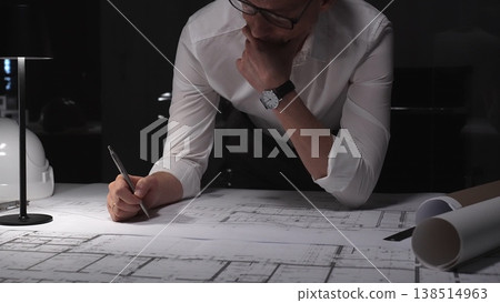 Architect carefully planning building blueprint, thinking about engineering design and development at late night workstation. Business and architect people concept Architect carefully planning building blueprint, thinking about engineering design and development at late night workstation. Business and architect people concept 138514963