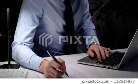 Professional businessman typing on laptop, working late in an office, demonstrating dedication and diligence. Audit and taxes in business 138514977