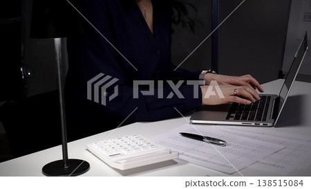 Woman's hands typing on laptop at office desk, working late night with calculator and financial documents. Audit and taxes in business 138515084